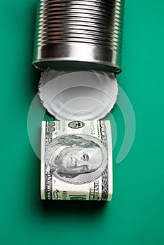 Dollars in an open tin can. Safeguarding cash, stash concept. Time to get the deferred, accumulated money. Green background