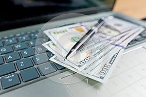 dollars and a pen lie on the laptop keyboard
