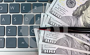 dollars and a pen lie on the laptop keyboard