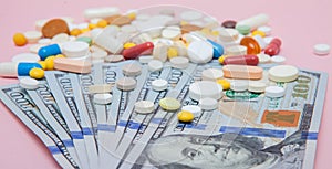 Dollars and pills on a pink background. Prescription medicine on dollars for pharmaceutical industry concept of high cost for heal