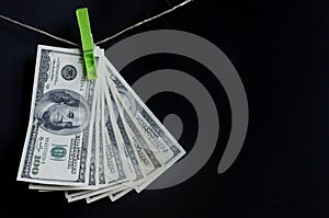 Dollars on the rope with clothespins. Fan of money on a dark background.