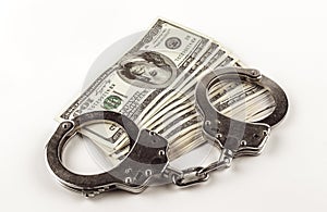 Dollars and steel handcuffs on a white background