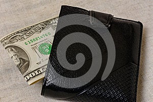 20 dollars sticking out of a wallet of dark leather on a gray background