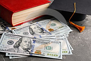 Dollars, student graduation hat and book. Tuition payments concept