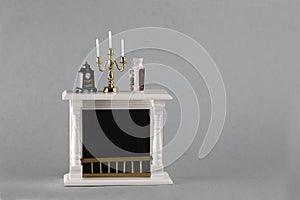 dollhouse interior - chimney with clock, candlestick, vase on mantelshelf isolated on gray background