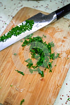 A dollop of chopped chives chopped with a knife on a cutting board