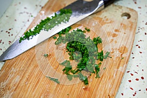 A dollop of chopped chives chopped with a knife on a cutting board
