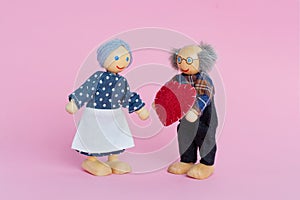 Dolls Elderly man and woman. Grandfather gives grandmother a heart a symbol of love and trust. Valentine`s day, love
