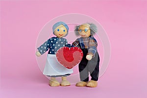 Dolls Elderly man and woman. Grandfather and grandmother hold a heart - a symbol of love and trust. Valentine`s day love