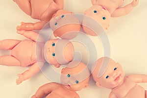 Dolls, lined up in a circle. One omitted. Concepts of abortion and childbirth. Toned