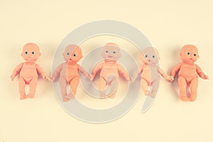 Dolls, lined up in a row. Concepts of abortion and childbirth. Toned