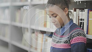 Dolly move of african american woman is reading book sitting on floor in school library.