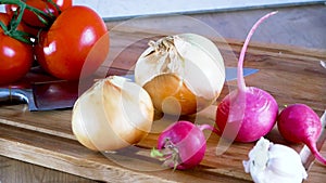 Dolly. Radish onion tomato knife and other vegetables on a kitchen board