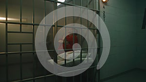 Dolly shot of female prisoner sitting on the bed in jail cell