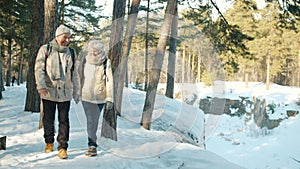 Dolly shot of happy couple senior woman and man enjoying walk in winter forest