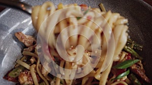 Dolly shot of man eating udon pasta noodles in bwl, focus on fork with winded noodles