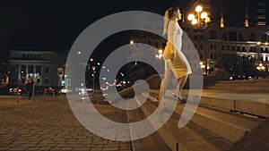 Dolly shot of slim woman in dress and high heels walking up the stairs at night