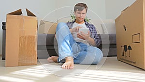 Dolly shot of young man using digital tablet while moving into a new house