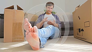 Dolly shot of young man using digital tablet while moving into a new house