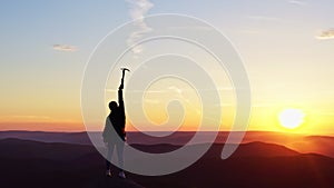 Dolly zoom effect of a woman happily raises her hands up on the top of a mountain at sunset.