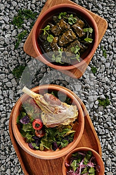 Dolma and Buglama with Lamb Shin, Vegetables, Fragrant Herbs on Gray Granite Chippings Top View photo