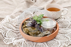 Dolma grape leaves with sauce on a clay plate on the table