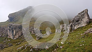 Dolomites of Italy. Dray stones and green hills in the fog