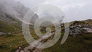 Dolomites of Italy. Dray stones, rocky trail, green hills in the fog