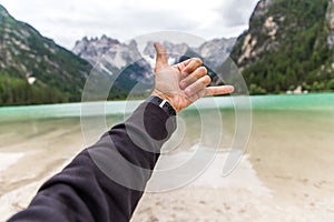 Dolomites, Italy - July, 2019: Man hand on background of majestic mountains, view of Lake Landro Lago di Landro Cristallo group