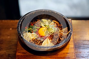 Dolsot bibimbap - Korean mixed rice, Include steamed rice, vegetables, pork and fried egg on top, served in a hot stone pot