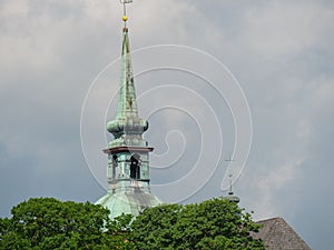 Dome of a cathedral and green trees under the cloudy sky in Schleswig-Holstein