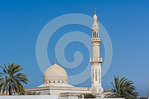 The dome and minaret of Maharba mosque and palm tree against blue sky in Dubai, United Arab Emirates