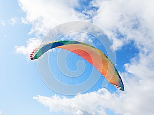 The dome of the paraglider with slings against the blue sky and clouds