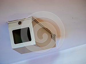 Dome surveillance camera in a protective steel white shroud with a transparent window. CCTV video camera on the white ceiling in