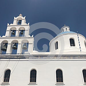 Domed church with bells in Santorini, Greece. Blue dome, white walls