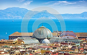 Domes of Galleria Umberto I towering over roofs of neighboring houses in Naples on background of Tyrrhenian Sea, Italy