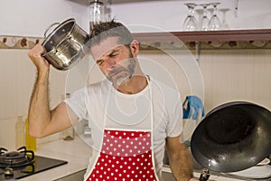 Domestic chores stress - lifestyle portrait of young attractive overworked and stressed home cook man in red apron hating