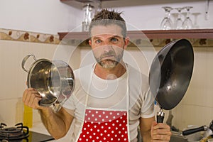 Domestic chores stress - lifestyle portrait of young attractive overworked and stressed home cook man in red apron hating