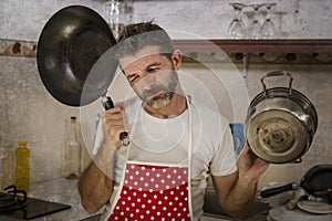 Domestic chores stress - lifestyle portrait of young attractive overworked and stressed home cook man in red apron hating