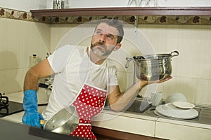 Domestic chores stress - young attractive overworked and stressed home cook man in red apron hating dishwashing feeling upset and