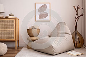 Domestic and cozy interior of living room with mock up poster frame, beige carpet, design pouf, lamp, decoration, wooden side