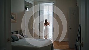 Domestic girl open curtains at morning indoors. Anonymous woman looking window