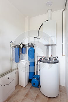A domestic household boiler room with a new modern gas boiler , heating electric warm water system and pipes.