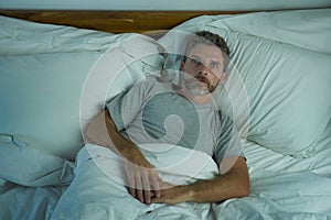 Domestic lifestyle high angle portrait of young handsome man awake at night with blue eyes wide open unable to sleep suffering