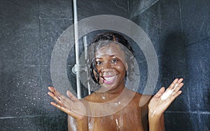 Domestic lifestyle portrait of young happy and beautiful black African American woman smiling happy taking a shower at home