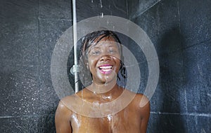 Domestic lifestyle portrait of young happy and beautiful black African American woman smiling happy taking a shower at home