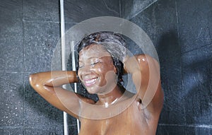 Domestic lifestyle portrait of young happy and beautiful black African American woman smiling happy taking a shower at home