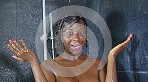 Domestic lifestyle portrait of young happy and beautiful black afro American woman smiling happy taking a shower at home bathroom