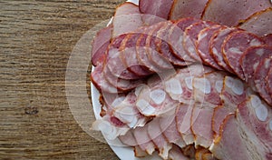 Domestic Meat Products. Meat Plate With Sliced Pork Ham, Bacon And Sausage On A Wooden Desk At A Side Of Image