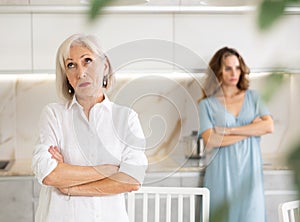 Domestic quarrel between mother and adult daughter in living room - relatives do not talk to each other